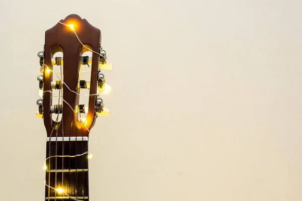 Akoestische gitaar verpakt in een lichtgevende bloemenslinger. Kerstcadeau — Stockfoto