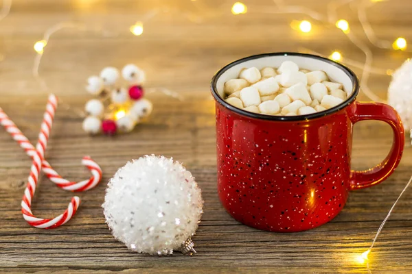 Xícara vermelha de cacau quente com marshmallows e bengalas doces. fundo com belas luzes de Natal bokeh . — Fotografia de Stock