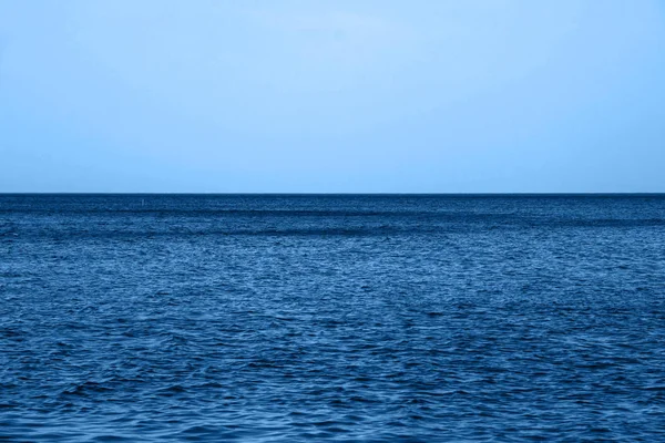 Calmo Azul ondas do mar superfície macia Oceano e céu azul em azul clássico cor da moda. antecedentes. Cor do ano 2020 . — Fotografia de Stock