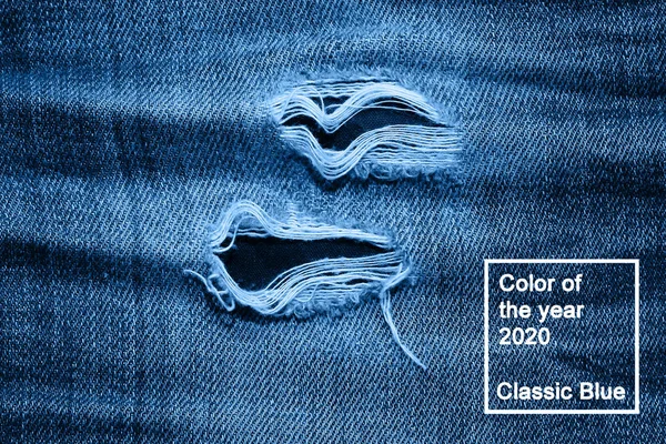 Makro konsistens jeans hål och trådar färgade i klassisk blå trendig färg. bakgrund. Årets färg 2020. — Stockfoto