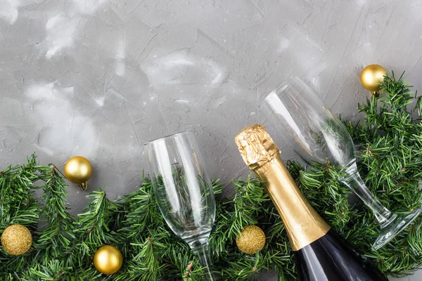 Deux verres à champagne avec boules d'or et bouteille de champagne dorée, sapin vert sur fond gris, espace de copie . — Photo