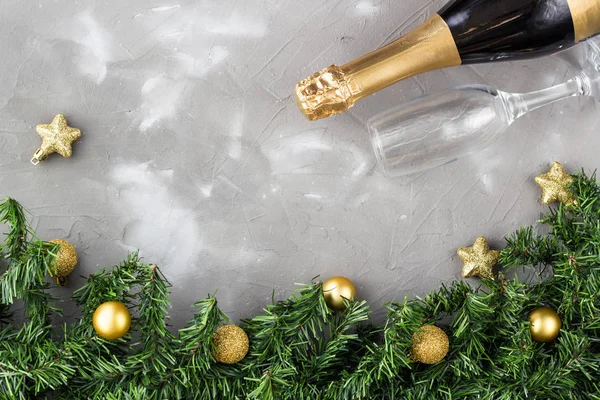 Dwie szklanki szampana ze złotymi kulkami i złotą butelką szampana, zielona jodła na szarym tle, przestrzeń do kopiowania. — Zdjęcie stockowe