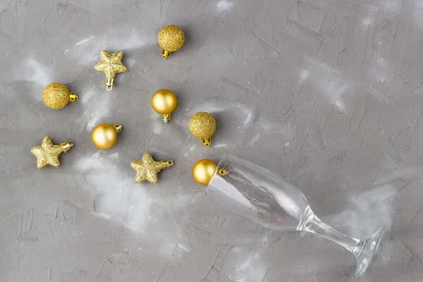 Champagne glas med gyllene bollar och stjärnor på grå bakgrund, kopiera utrymme. Julkoncept. Ovanifrån, platt ligg — Stockfoto