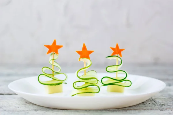 Yaratıcı konsept, salatalık, peynir ve havuçtan oluşan Noel ağaçları hazırladı. Yeni yıl partisi için komik çocuk yemekleri.