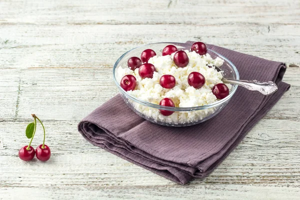 Colazione da ricotta con ciliegia in ciotola trasparente su sfondo bianco in legno — Foto Stock