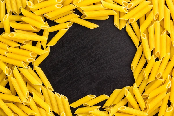 Frame of A pile of penne pasta on black background with copyspace — Stock Photo, Image