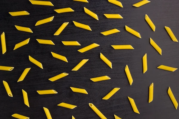 Muster eines Haufens Penne-Pasta auf schwarzem Hintergrund — Stockfoto
