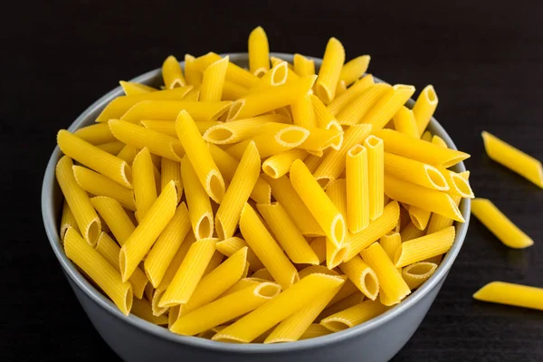 Fond noir avec penne crue italienne ou pâtes dans un bol avec espace de copie — Photo