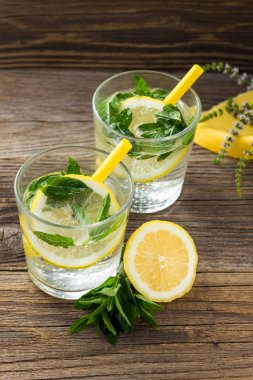Lemonade or mojito cocktail with lemon and mint with ice. Cold summer refreshing drink decorated with yellow napkin