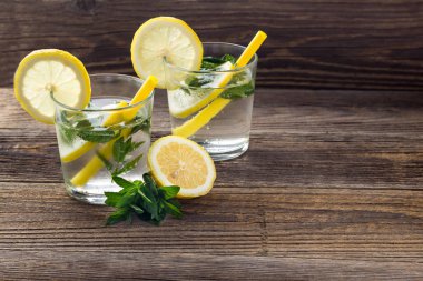 İki bardak limonlu limonata, naneli ve ahşap zemin üzerinde buz küpleri. Yaz içeceği
