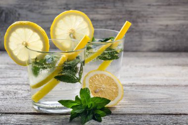 İki bardak limonlu limonata, naneli ve ahşap zemin üzerinde buz küpleri. Yaz içeceği