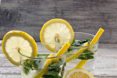 İki bardak limonlu limonata, naneli ve ahşap zemin üzerinde buz küpleri. Yaz içeceği