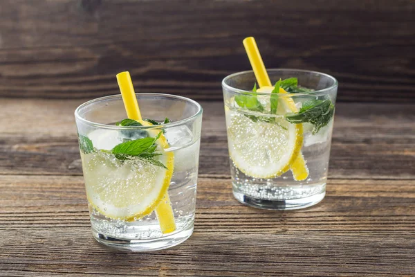 Dos vasos de limonada con limón, menta y cubitos de hielo sobre fondo de madera. Bebida de verano — Foto de Stock