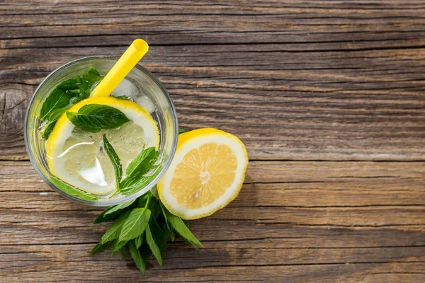 Agua con limón y menta en un vaso sobre fondo de madera. Bebida fresca de limonada de verano — Foto de Stock