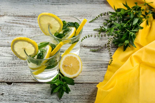 Lemonade or mojito cocktail with lemon and mint with ice. Cold summer refreshing drink decorated with yellow napkin — Stock fotografie