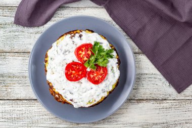 Domatesli kabak keki ve beyaz ahşap arka planda taze maydanoz. Peçeteli üst görünüm