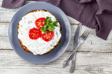 Domatesli kabak keki ve beyaz ahşap arka planda taze maydanoz. Peçete çatalı ve bıçakla üst manzara