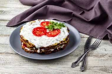 Domatesli kabak keki ve beyaz ahşap arka planda taze maydanoz. Peçete çatalı ve bıçakla