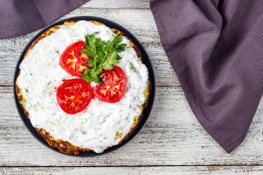 Domatesli kabak keki ve beyaz ahşap arka planda taze maydanoz. Peçeteli üst görünüm