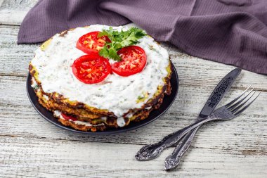 Domatesli kabak keki ve beyaz ahşap arka planda taze maydanoz. Peçete çatalı ve bıçakla