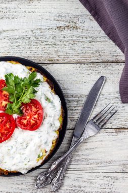 Domatesli kabak keki ve beyaz ahşap arka planda taze maydanoz. Peçete çatalı ve bıçakla üst manzara