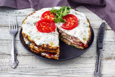 Domatesli kabak keki ve beyaz ahşap arka planda taze maydanoz. Peçete çatalı ve bıçakla