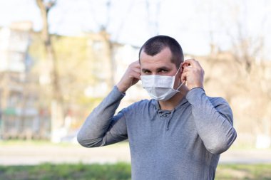 Kafkasyalı bir adam sokakta yüz maskesi takıyor. Enfeksiyonu durdur. Çin salgını koronavirüs konsepti