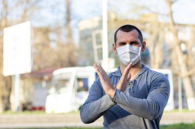 Koruyucu tıbbi maskeli bir adam sokakta kamera jest sinyaline bakıyor. Enfeksiyonu durdur. Çin salgını koronavirüs konsepti