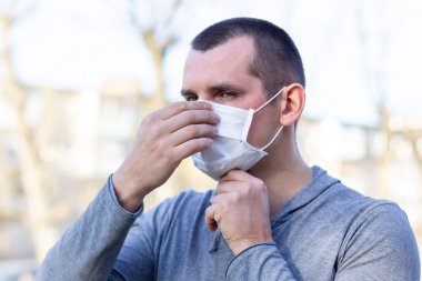 Kafkasyalı bir adam sokakta yüz maskesi takıyor. Enfeksiyonu durdur. Çin salgını koronavirüs konsepti
