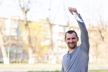 Kafkasyalı mutlu bir adam sokakta tıbbi maske tutuyor. Adam maskesini çıkardı. Virüsü yenme konsepti. Biraz temiz hava.
