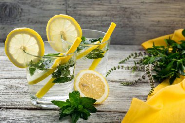 Limonata ya da limonlu mojito kokteyli ve buzlu nane. Soğuk yaz ferahlatıcı içeceği. Ahşap arka planda sarı peçeteyle süslenmiş.