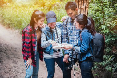 Arkadaşlarıyla ormanda yürüyüş yapıyor. Kırsal bölgede yürü ve haritayı oku. Takım çalışması açık hava aktivitesi..