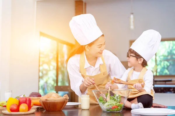 Asian family in the kitchen. Mom teaching son for cook healthy food in summer holiday.