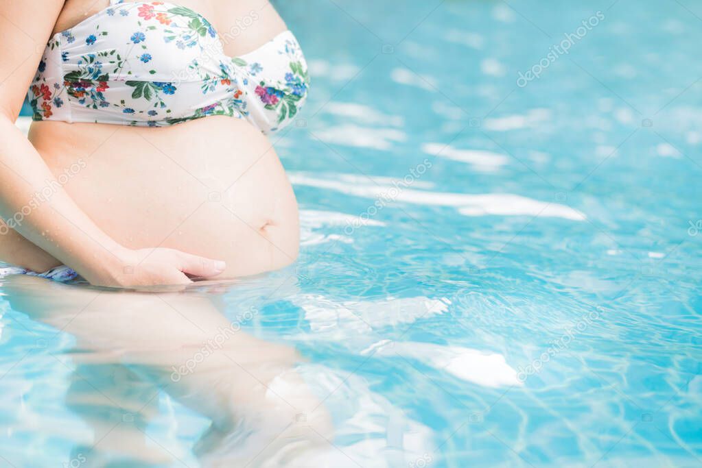 Asian pregnant woman with big belly. Relax and exercise at swimming pool