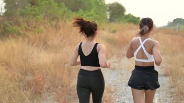 Yavaş hareket eden sporcu kadın arkadaşıyla koşuyor. Yazın Asyalı kadın dayanıklılık eğitimi. Sağlıklı yaşam tarzı ve spor anlayışı.