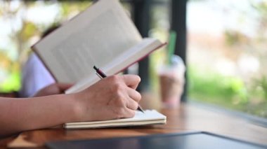 Bir kadının kitap ve defterle çalışırken çekilmiş görüntüleri.