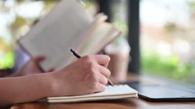 Bir kadının kitap ve defterle çalışırken çekilmiş görüntüleri.