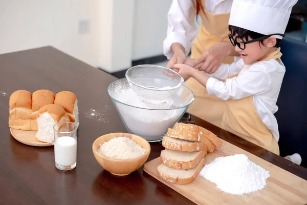 Asian family in the kitchen. Mom teaching son for cook healthy food in summer holiday.