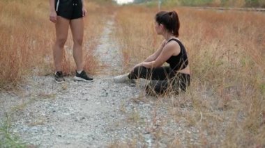 Koşucu düşüyor ve bacakları yaralı. Sporcu arkadaş yürümeye yardım ediyor. Sağlıklı yaşam tarzı ve spor takım çalışması kavramı.