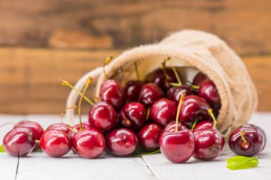 Çiftlikten taze kiraz, tatlı ve ekşi meyve, ahşap masa arka planı.