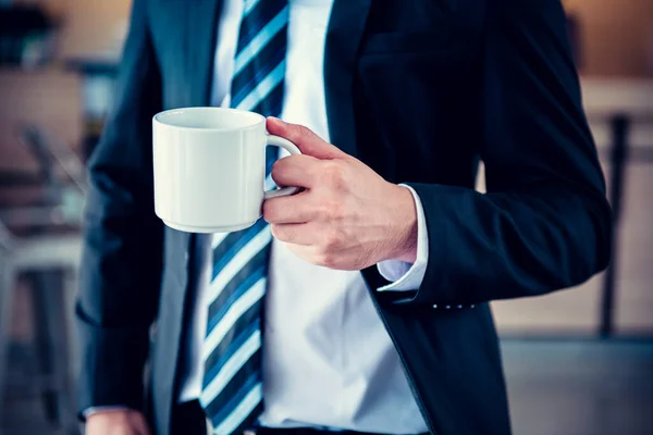 コーヒーを飲みながらオフィスに立つビジネスマン — ストック写真