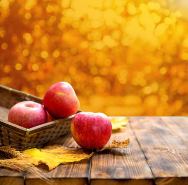 close-up shot of ripe fresh apples with fallen maple leaves on wooden table for background clipart