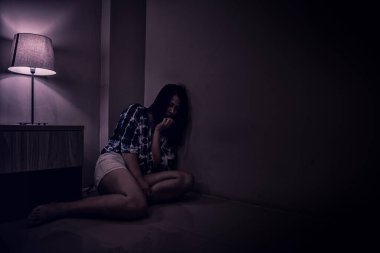 Depresyondaki kadın karanlık odada yalnız. Akıl sağlığı sorunu, travma sonrası stres bozukluğudur..