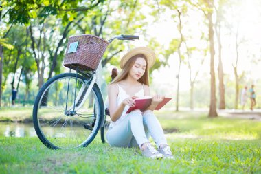 Öğrenci parkta kitap okuyor. Üniversiteye gitmeye hazır..