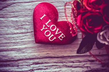 Beyaz ahşap masa üstünde pembe güllü yumuşak kırmızı kalplerin yakın plan çekimi, Sevgililer Günü konsepti