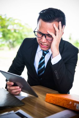 Asyalı İşadamı tablet üzerinde çalışıyor, çalışmak için baskı görüyor ve başarısız oluyor