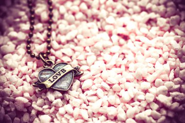 Sevgililer Günü konsepti olan pembe çakıl taşlı kolyenin yakın plan fotoğrafı.