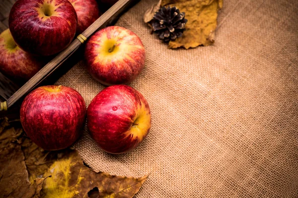 木のテーブルの上に落ちたカエデの葉を背景に熟した新鮮なリンゴのクローズアップショット — ストック写真