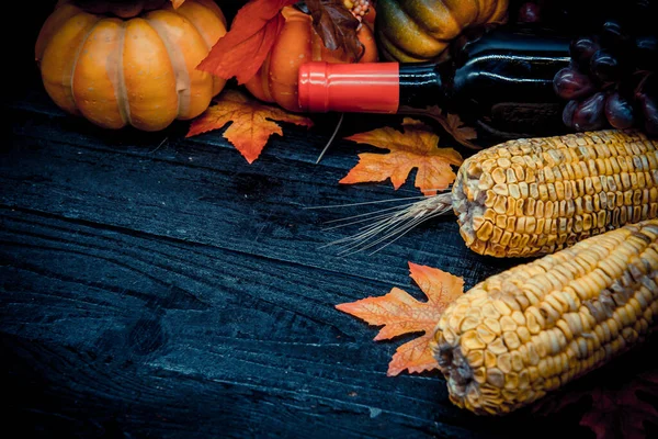 収穫したカボチャとブドウとコーンをワインボトルでクローズアップして感謝祭の日の背景に — ストック写真