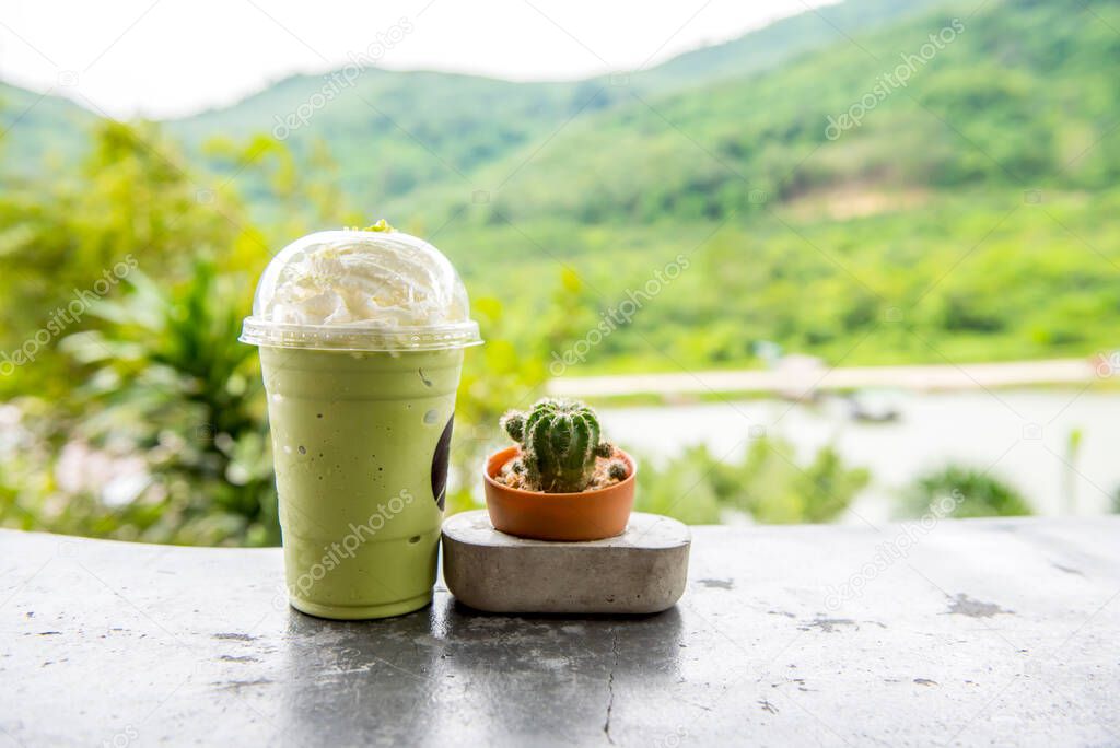 plastic cup of green tea frappe in front of natural background